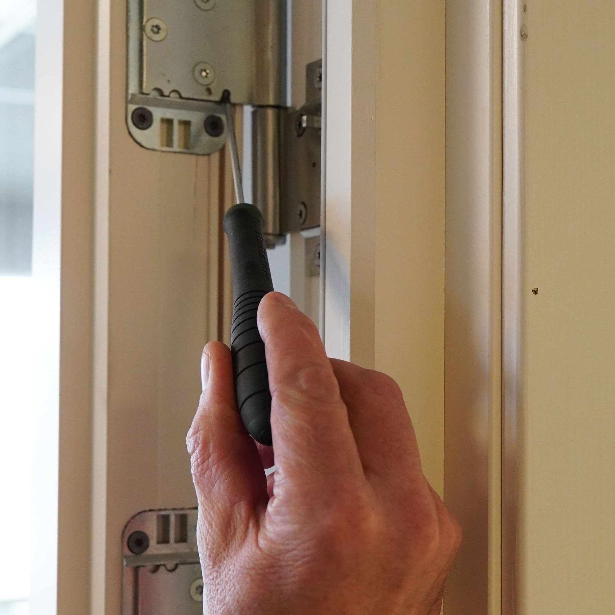 Hand holding screwdriver in door frame