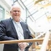 en-mann-i-dressjakke-står-ved-rekkverk-og-ser-i-kamera