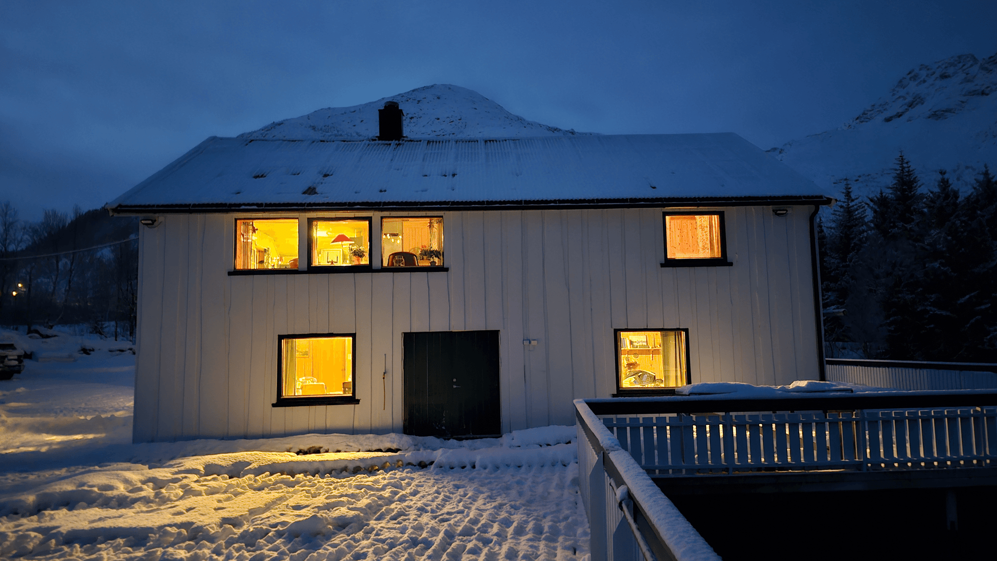 Hus med fjell bak og lys i vinduene