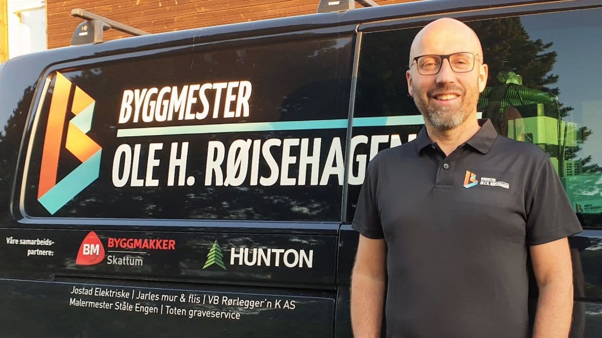 Mann står foran en bil og ser i kameraet