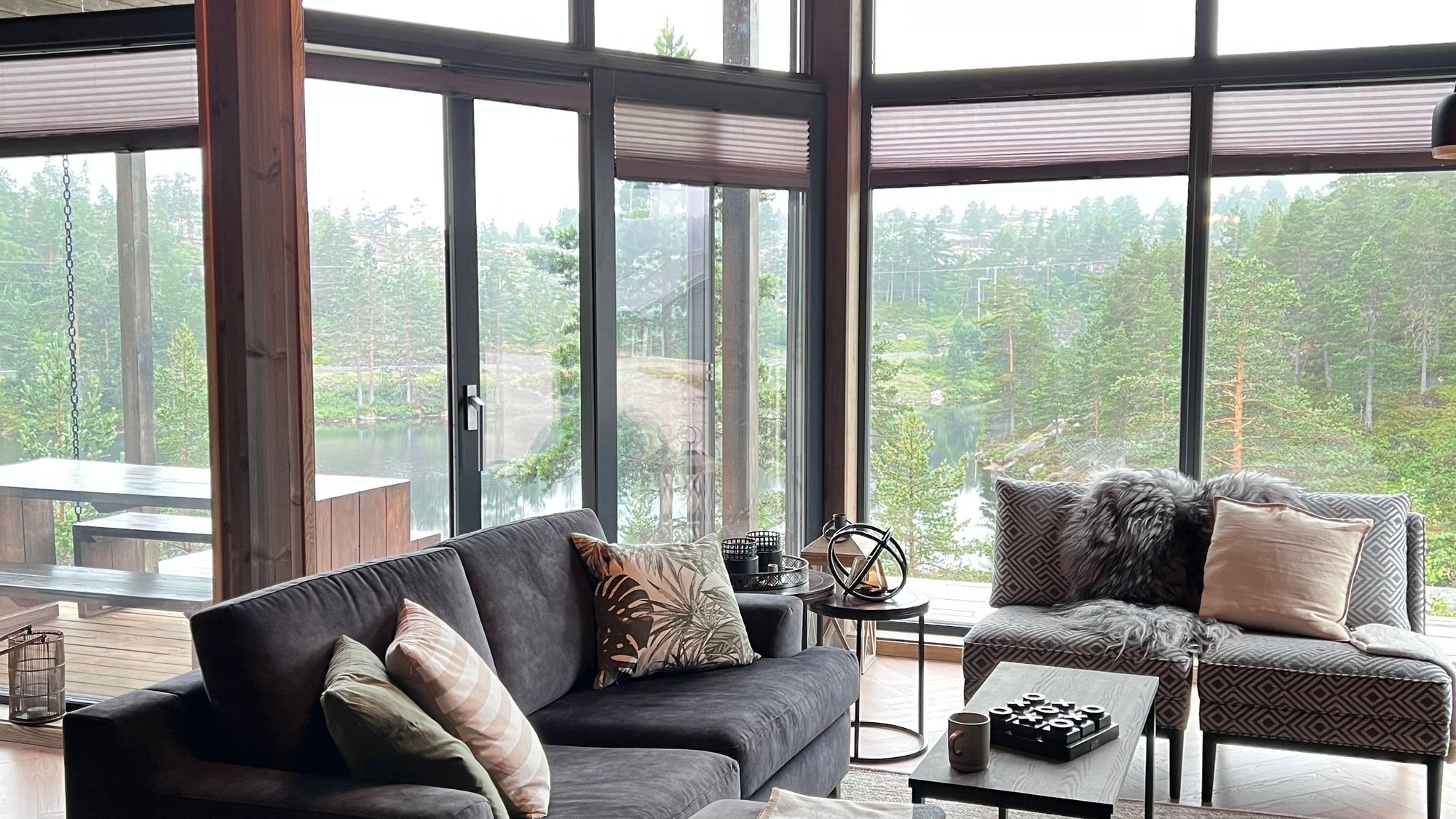 Sofa foran store vinduer med skog utenfor