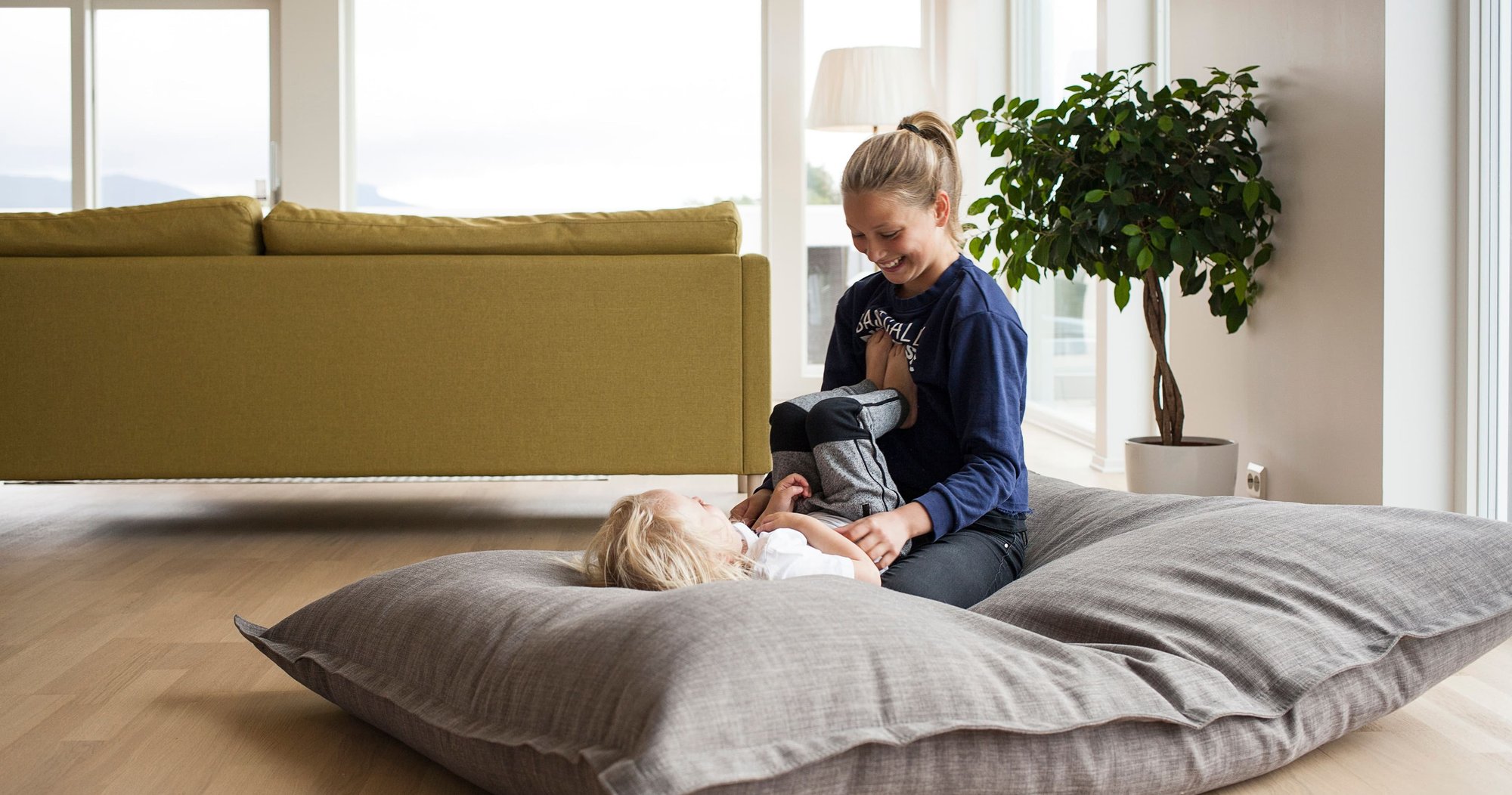 To barn leker i en saccosekk på gulvet