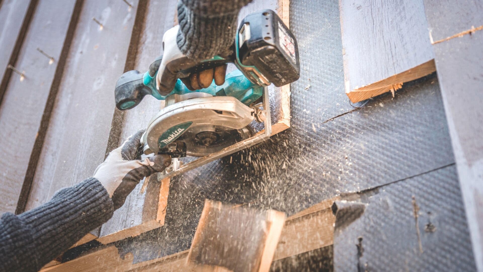 To hender holder sag som skjærer panel på hus