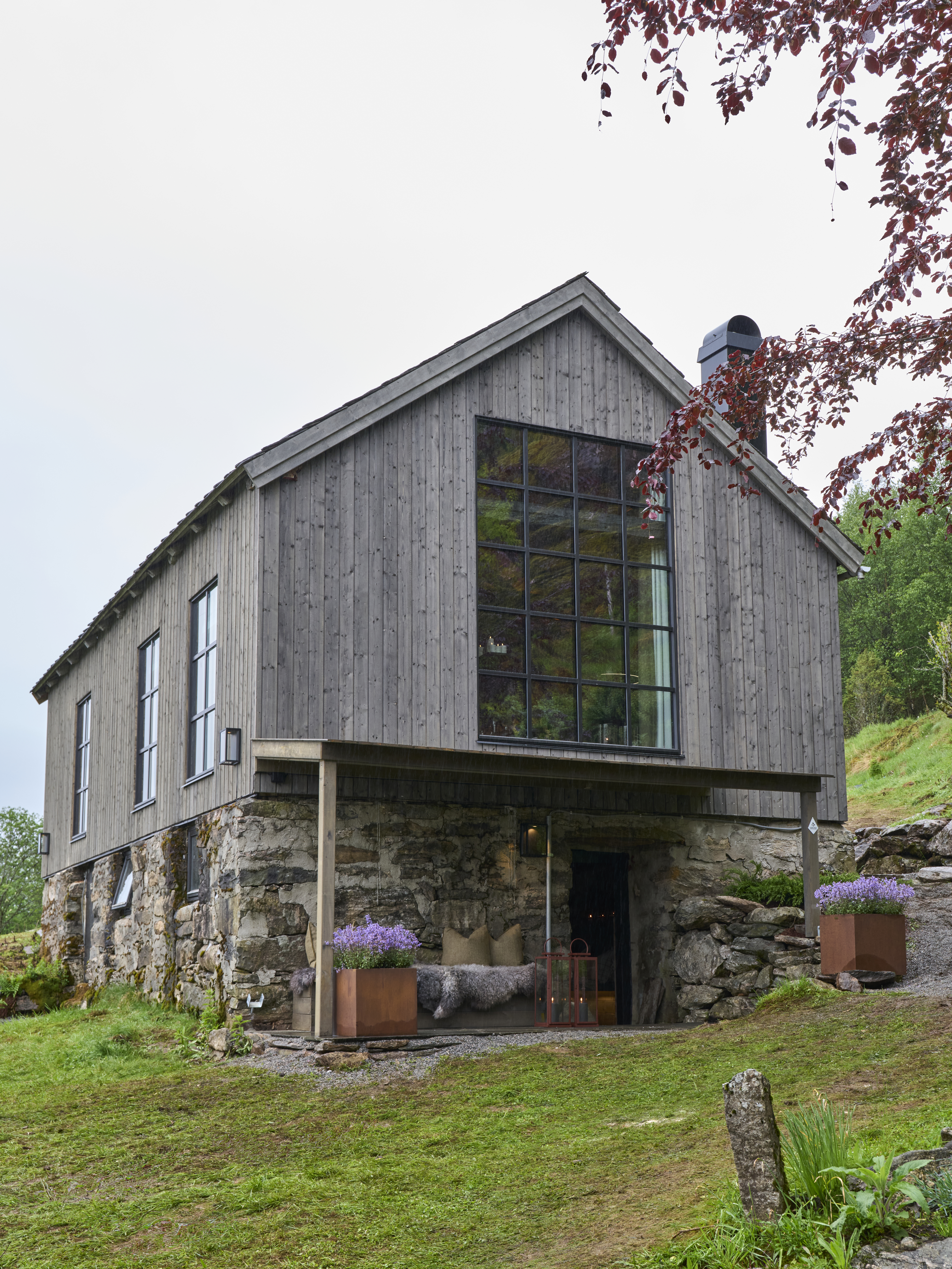 Tradisjonell låve med store vindusflater og natursteinsgrunnmur i Naustdal.