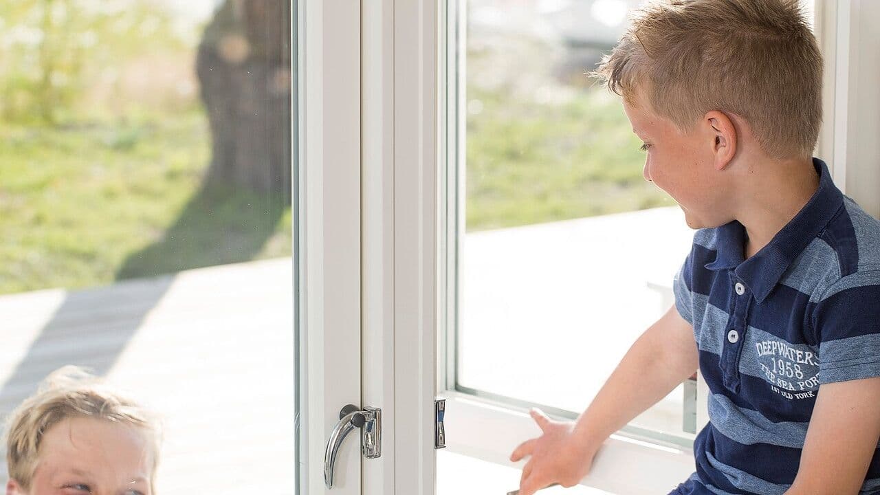 En liten gutt sitter i et vindu og snakker med en utenfor