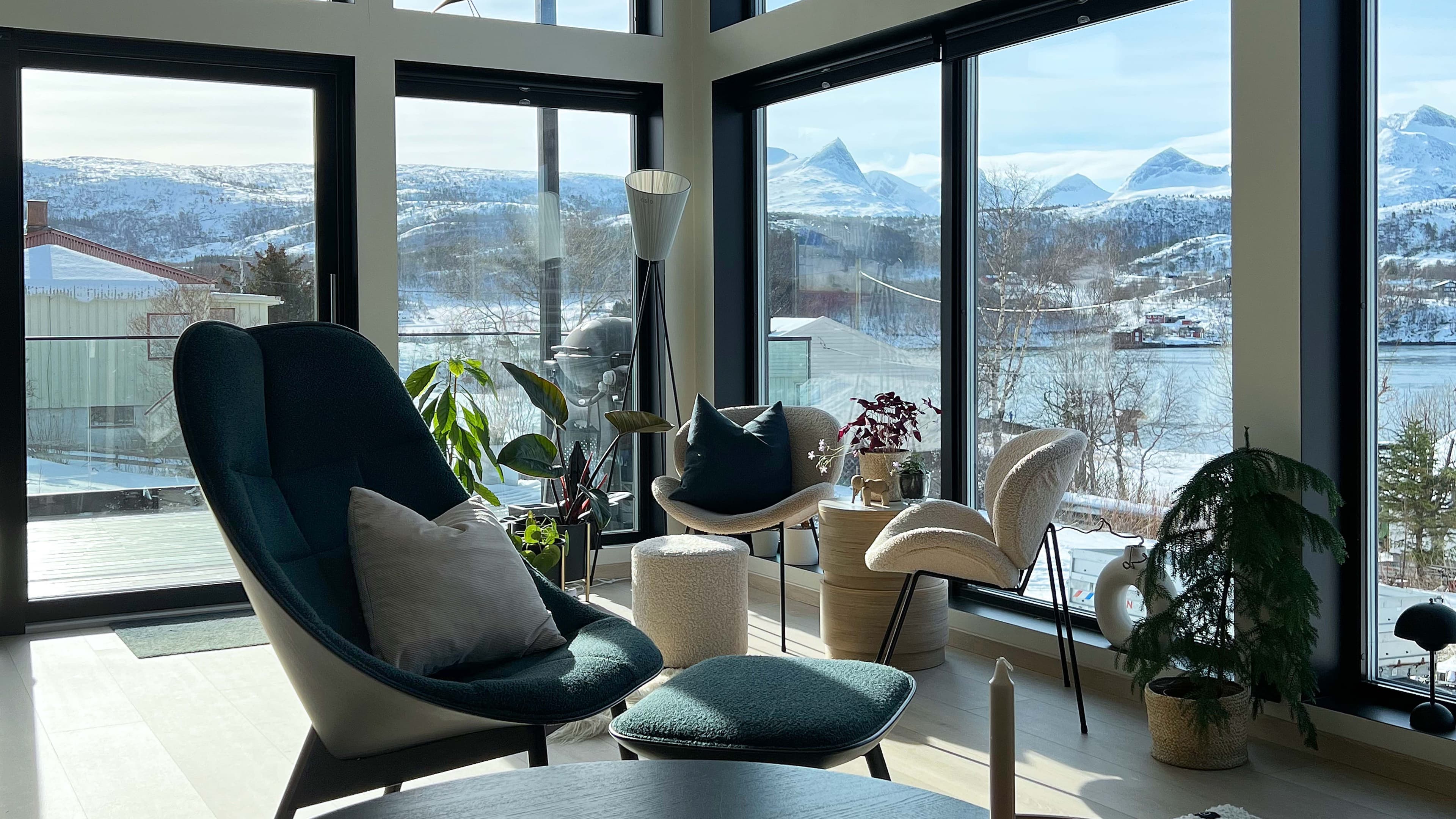 Stue med store sorte vinduer og utsikt til fjell