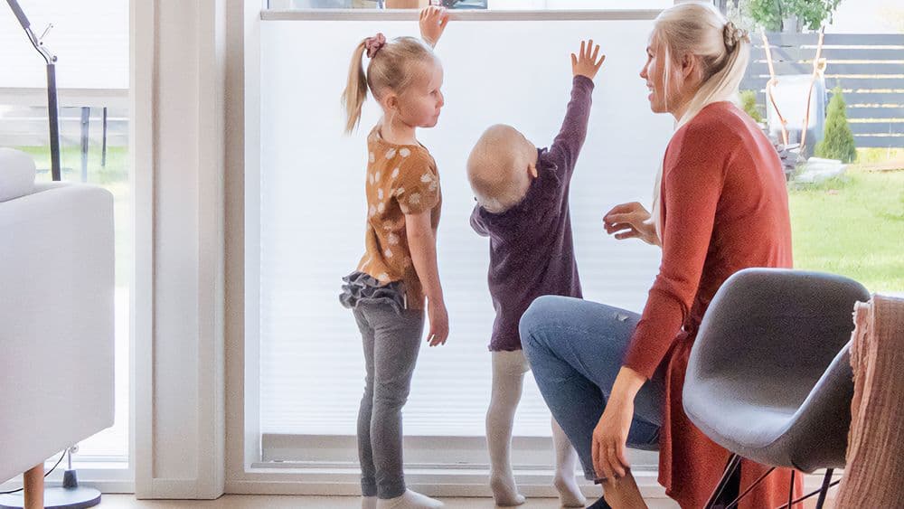 To barn og mor ved en plissegardin
